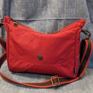 PacSafe Citysafe 200-series crossbody anti-theft bag in red w/tan interior.